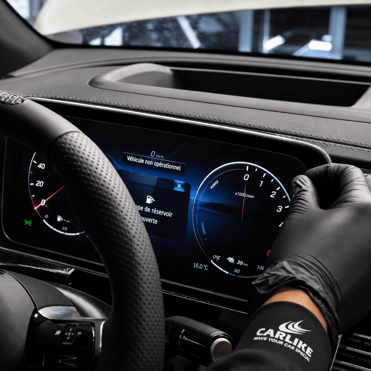 Mains gantées posant un PPF intérieur transparent sur l’écran numérique du tableau de bord d’une voiture
